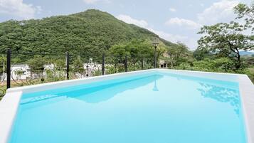 Una piscina con vistas a una montaña y un edificio blanco al fondo.