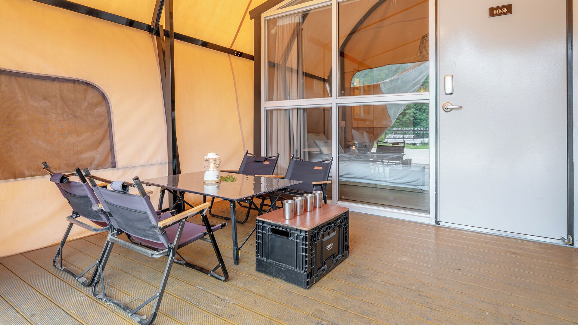 A tented room with a table, chairs, and a suitcase.