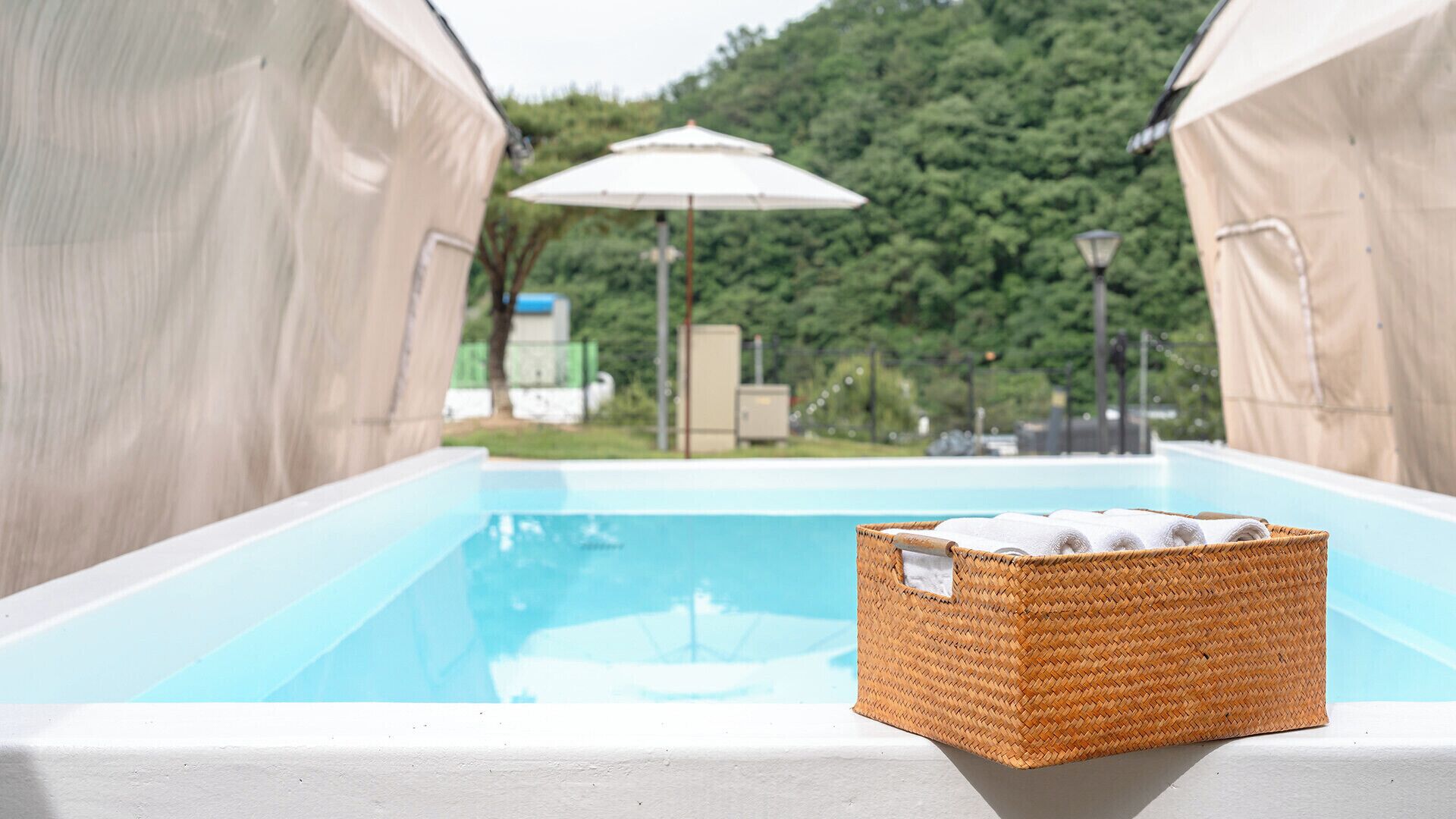 Una piscina con una cesta de mimbre que contiene toallas.