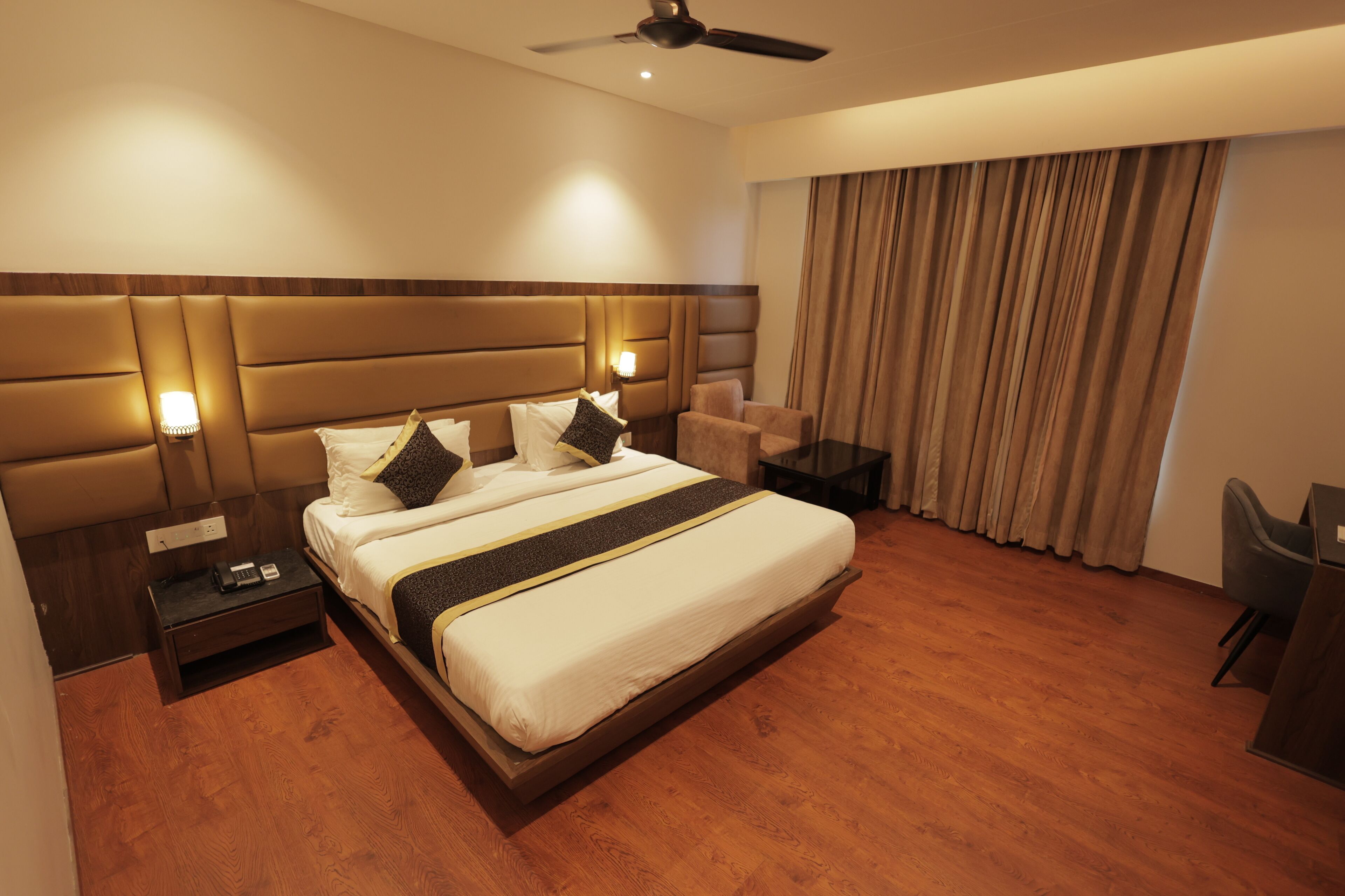 A hotel room with a large bed, bedside tables, a desk, and a chair.