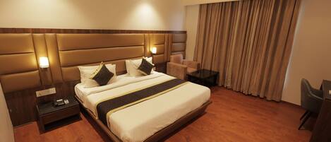 A hotel room with a large bed, bedside tables, a desk, and a chair.