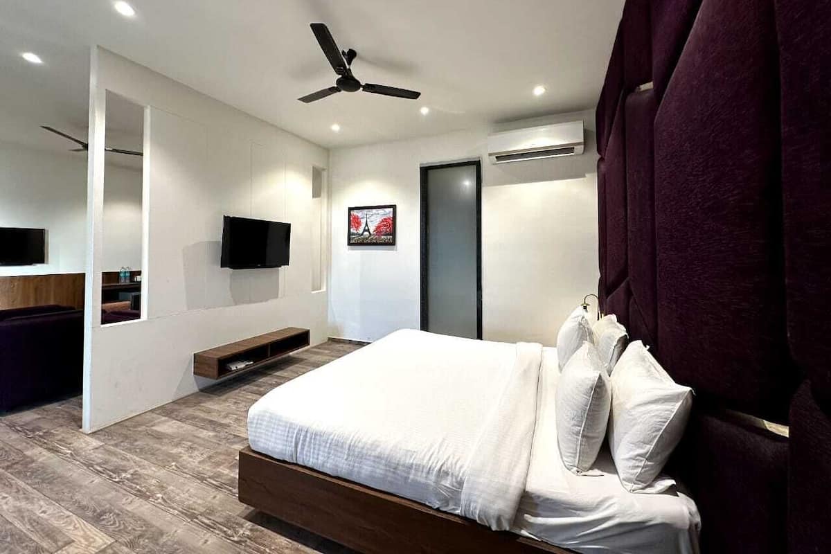 A modern bedroom with a bed, a ceiling fan, a mounted TV, and a door with a glass panel.