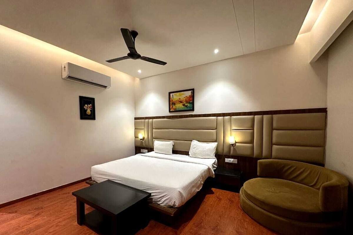 A modern hotel room with a large bed, a desk, a chair, and a ceiling fan.