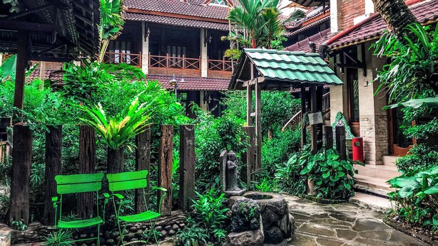 A courtyard with traditional architecture, stone pathways, and lush greenery.