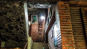 A staircase with stone walls and brick elements, leading to a room with a framed picture and a decorative wall piece.