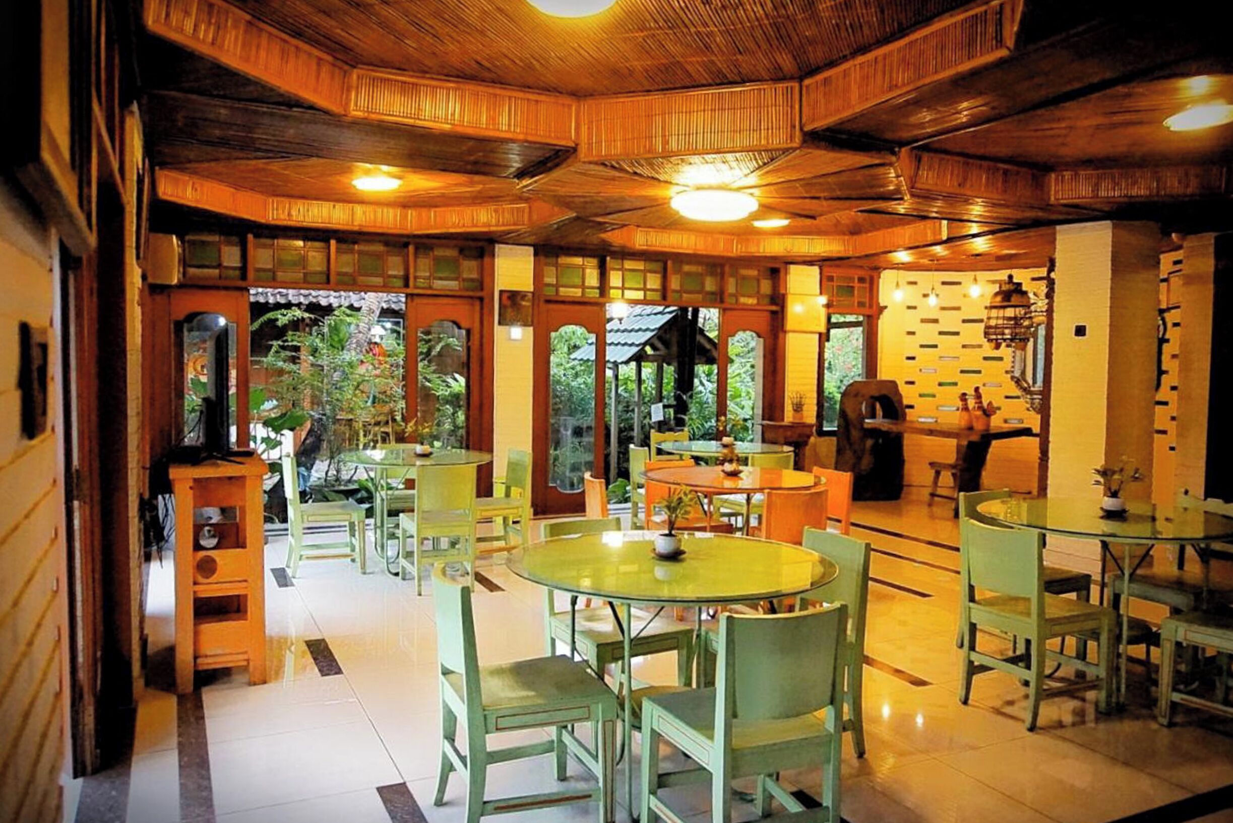 A restaurant with wooden ceiling, green chairs, and tables.