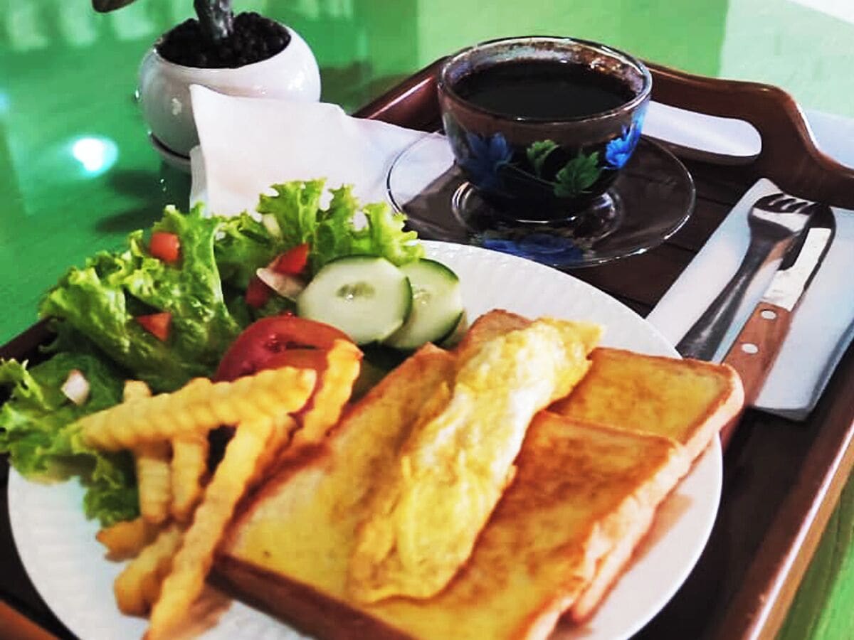 Un plato con tostadas, papas fritas, ensalada y una taza de café en una bandeja.