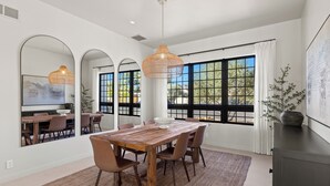 A dining area with a wooden table, chairs, and a large window with a view of greenery.