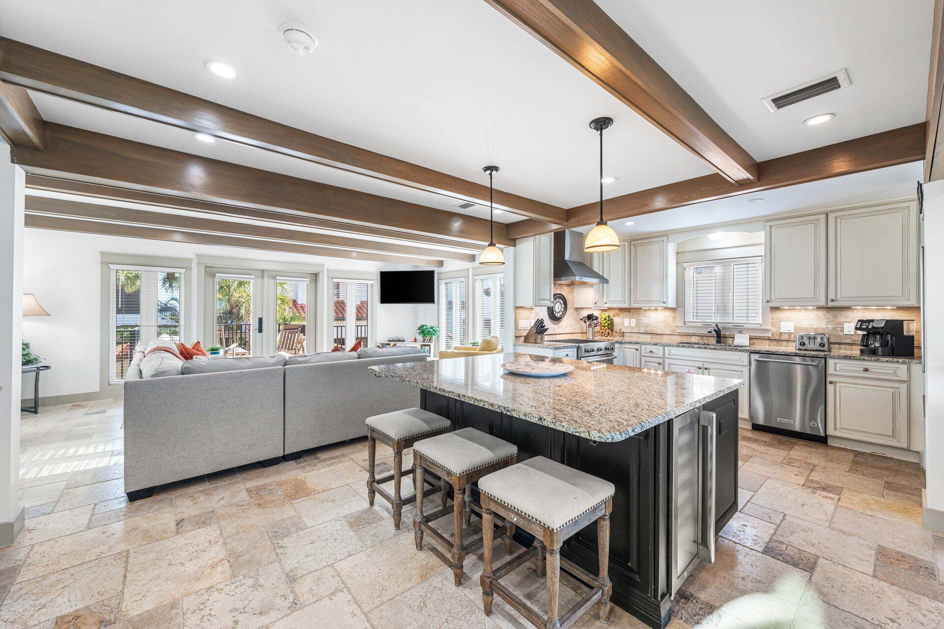A modern kitchen with a large island, bar stools, and stainless steel appliances.