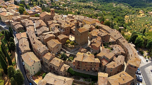 Une vue aérienne d’une ville historique, caractérisée par des bâtiments très rapprochés, des rues étroites et une tour centrale imposante.