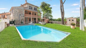 Une maison en pierre à deux étages avec une piscine dans le jardin.