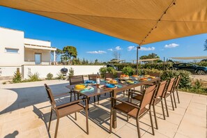 A covered outdoor dining area with a table set for six, surrounded by chairs.
