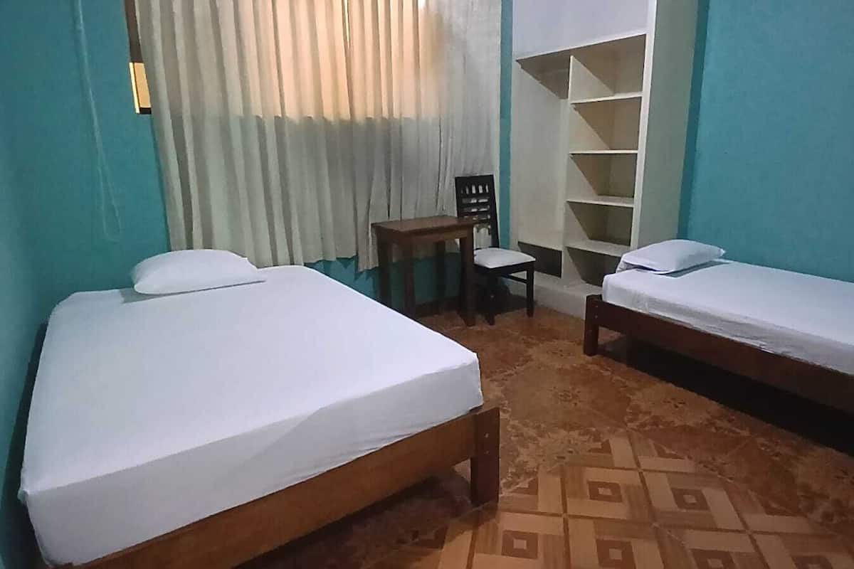 Une chambre avec deux lits simples, un petit bureau avec une chaise et une armoire.