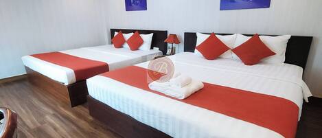 A hotel room with two beds, each with red and white bedding, and a wooden floor.