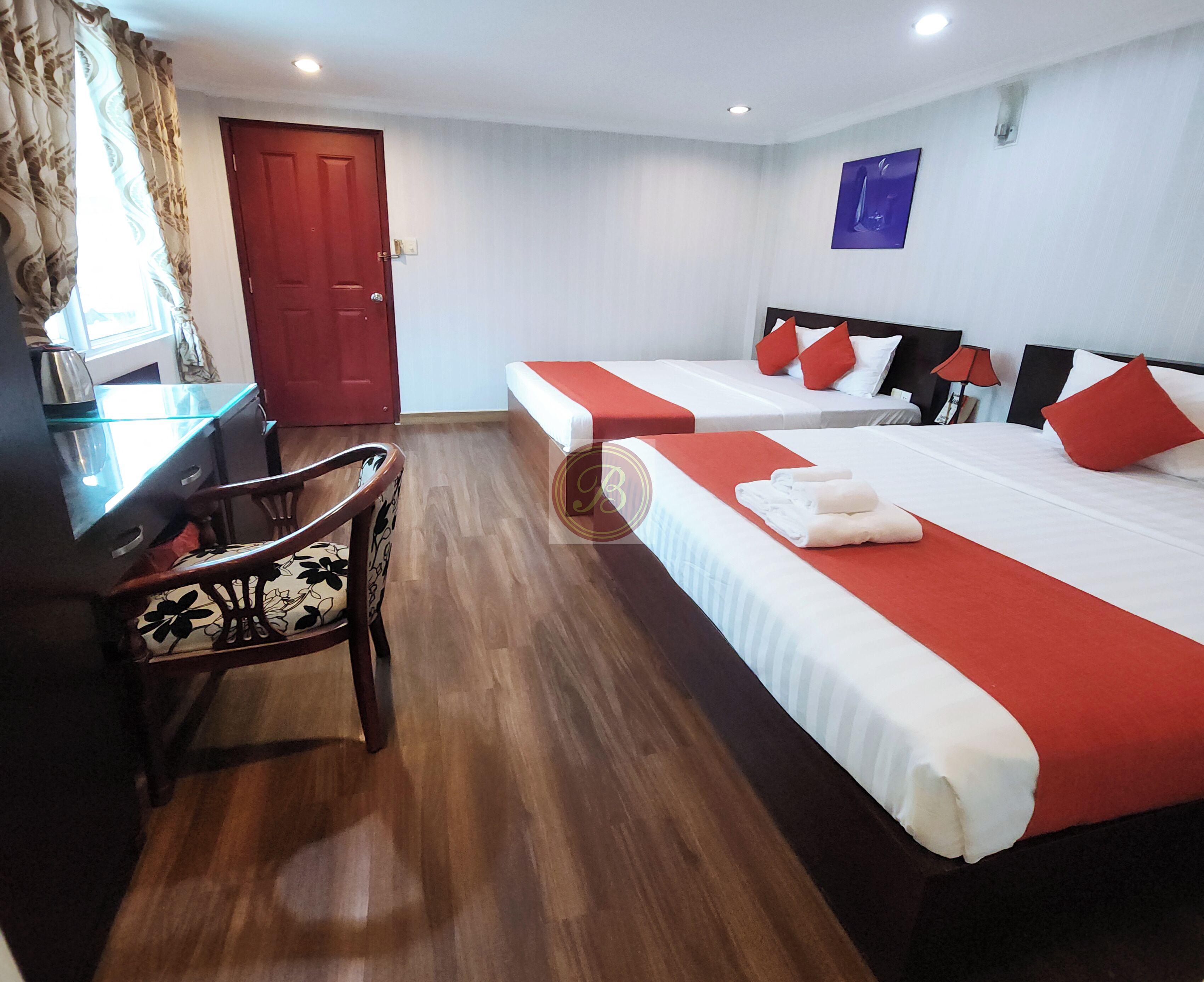 A hotel room with two beds, a desk, and a chair.