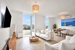 Ein modernes Wohnzimmer mit einer Couch, einem Esstisch und einem an der Wand befestigten Fernseher.