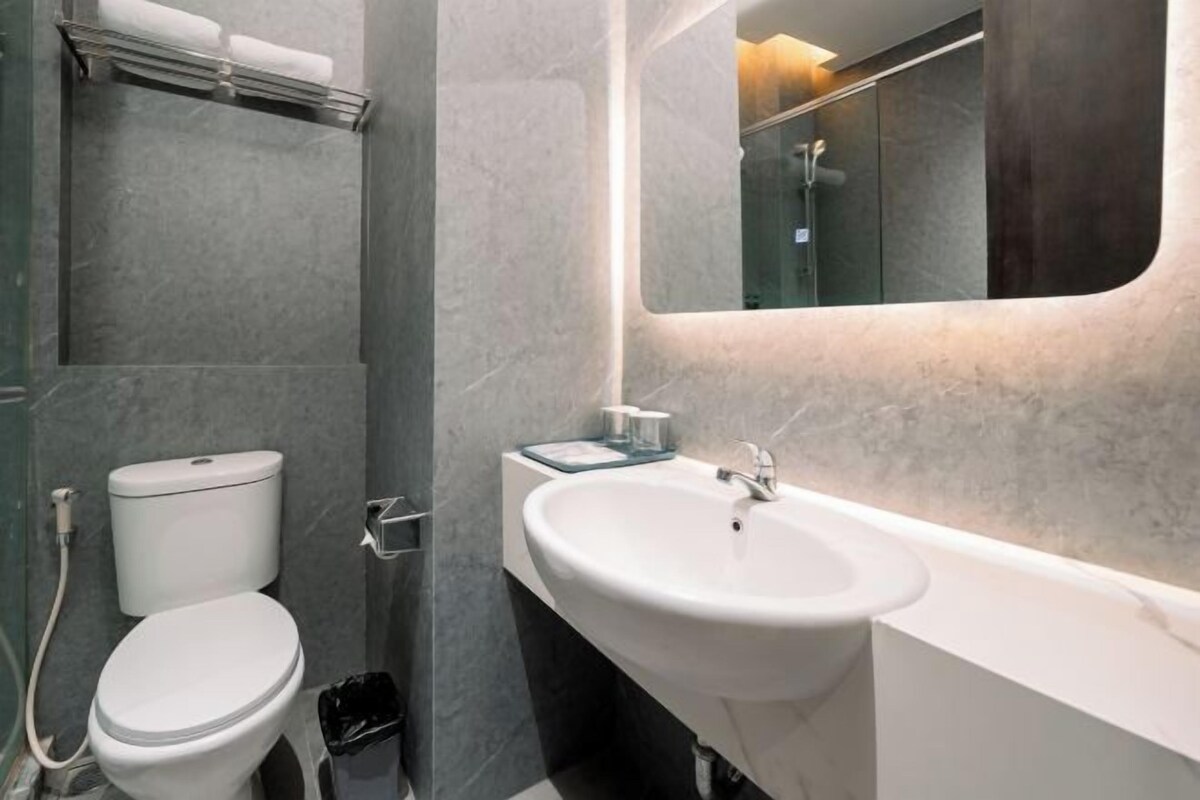 A modern bathroom with a toilet, sink, and mirror.