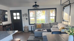 A modern living room with a grey sofa, wooden coffee table, and a black dining table. - Over 200’ of  lakefront all sand on Washington lake with a view of Shawano lake! (Shawano)