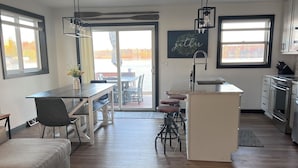 A modern kitchen with a central island, a dining area with a table and chairs, and a cozy seating area with a sofa. - Over 200’ of  lakefront all sand on Washington lake with a view of Shawano lake! (Shawano)