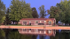 A house with a large garage, a covered porch, and a swimming pool in front. - Over 200’ of  lakefront all sand on Washington lake with a view of Shawano lake! (Shawano)