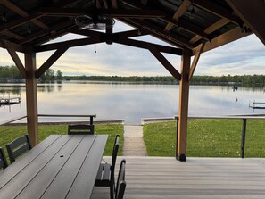 Un espace extérieur abrité, aménagé avec des sièges, et offrant une vue sur un lac paisible et un quai.