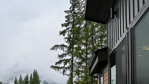 Eine Holzterrasse mit Tisch und Stühlen mit Blick auf einen Wald und Berge.