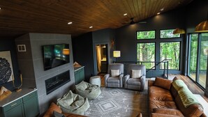 Ein modernes Wohnzimmer mit einer großen Ledersofa, einem Flachbildfernseher und einem Deckenventilator.