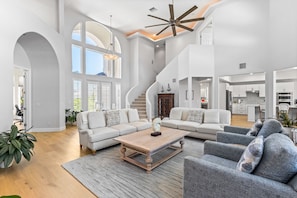 Relax in this spacious living area with a high ceiling, featuring a curved staircase and comfortable seating for relaxation.