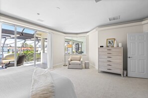 Relax in this serene bedroom with a large bed, glass door leading to a balcony, and a stylish dresser.