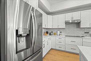 Enjoy cooking in this well-equipped kitchen with an oven, stainless steel range hood, and wooden countertop.