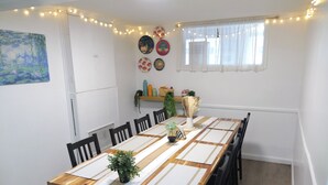 Comedor con una mesa de madera larga, sillas negras y luces colgantes.