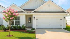 A single-story house with a garage, a front door, and a small porch. - Sleeps 10 - The Salty Piper - Community pool (Santa Rosa Beach)