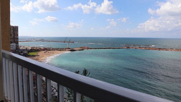 A coastal view from a balcony overlooking turquoise waters, a sandy beach, and a distant pier. -  NOUR1
Sea view (Alexandria)