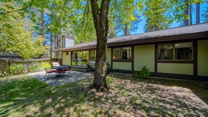 A modern building with a large tree in front, a patio with outdoor furniture, and a view of the surrounding forest. - 2 bed/ 2 bath single story condo in the heart of Graeagle Meadows (Graeagle)