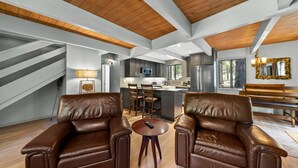 A spacious living area with leather sofas, a central island, and a kitchen in the background. - Escape to Tranquility in This Beautiful Forest-Edge Retreat (Graeagle)