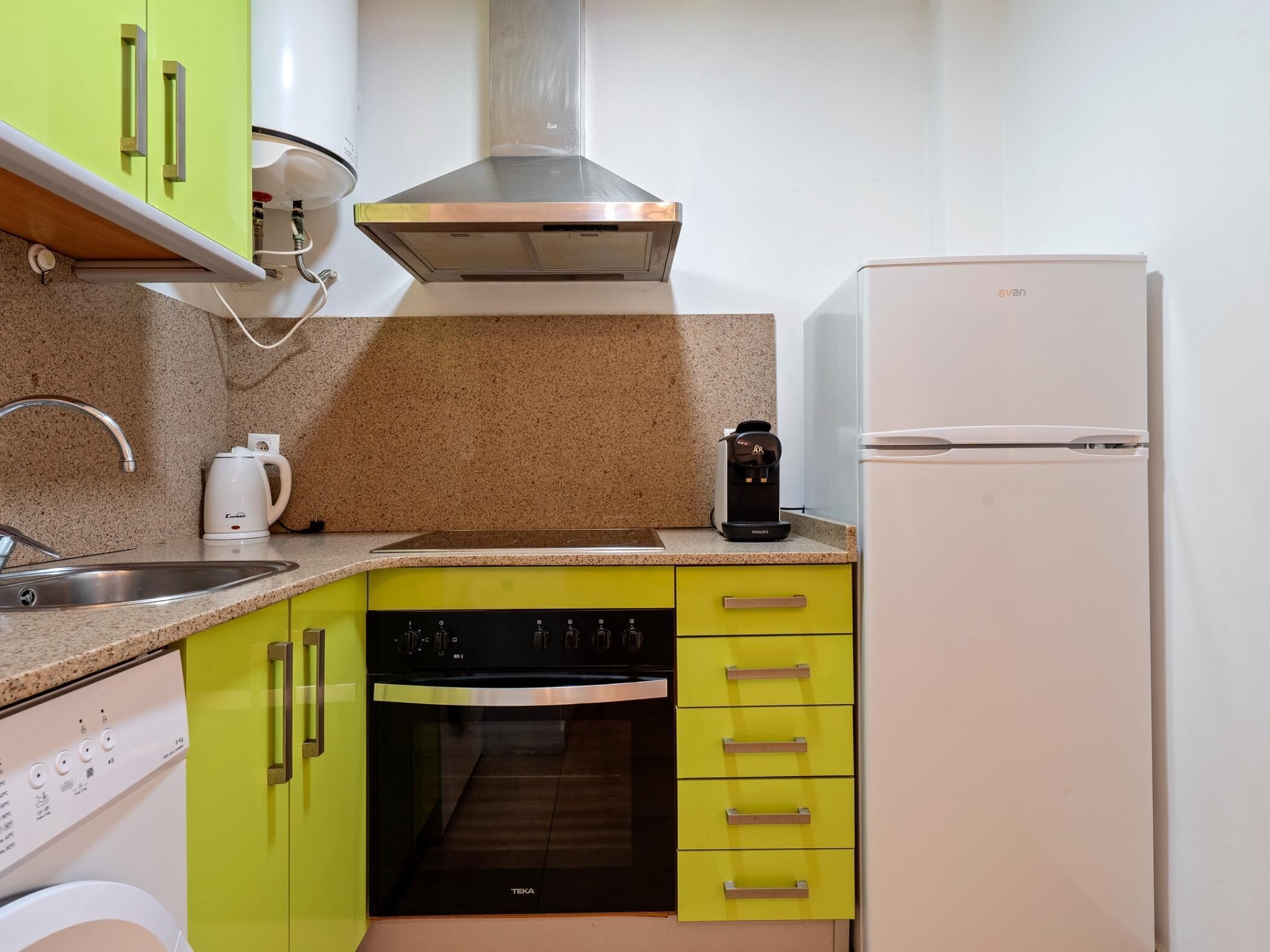 Una cocina compacta equipada con lavavajillas, horno, cafetera y refrigerador.