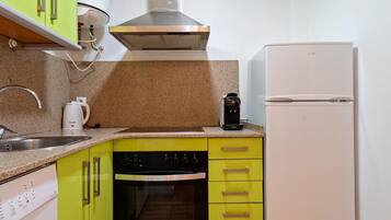 Una cocina compacta equipada con lavavajillas, horno, cafetera y refrigerador.