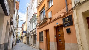 Una calle estrecha flanqueada por edificios. Un cartel indica "Massegu" a la derecha.
