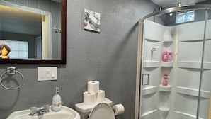 Un baño con lavamanos, inodoro y ducha con mampara de vidrio.