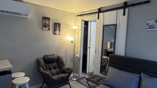 Un dormitorio con cama, una silla, un escritorio y una lámpara.