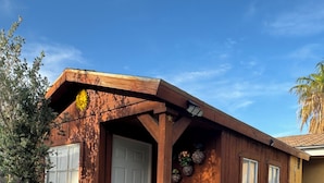 Una casa de madera con puerta blanca, un porche pequeño y una ventana.