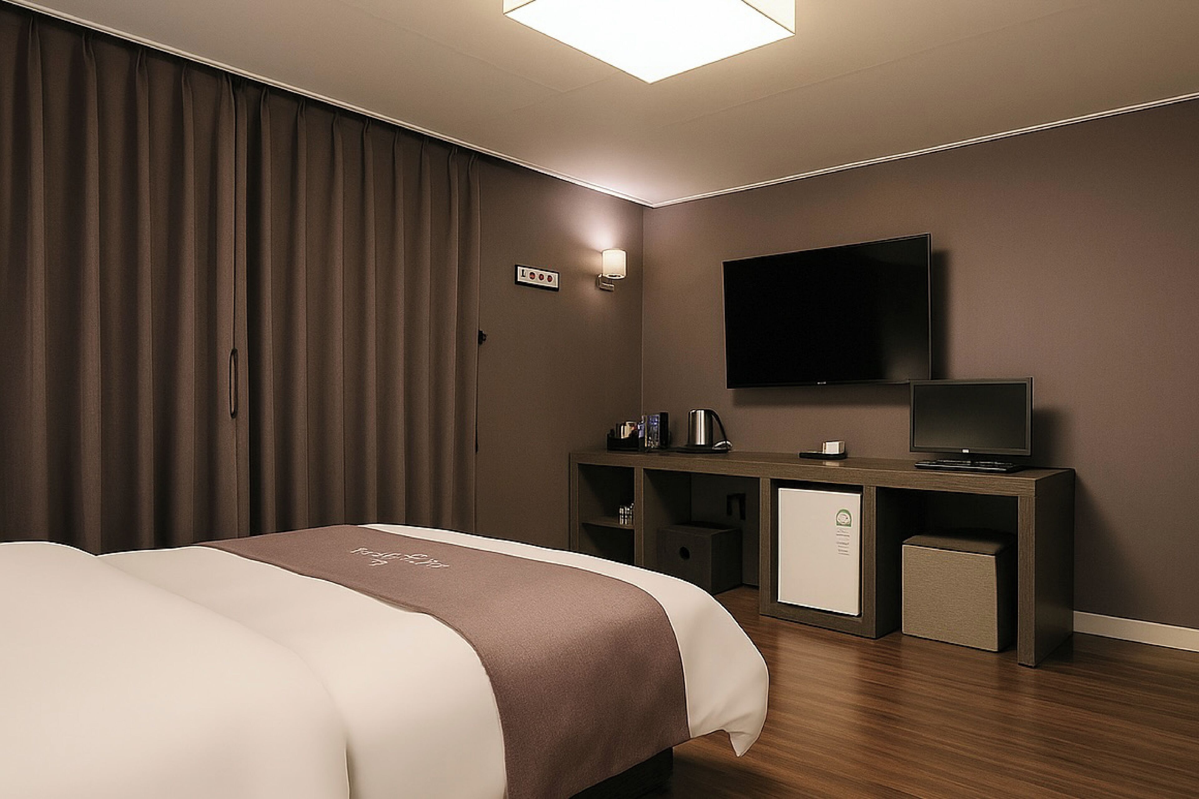 A hotel room with a bed, a desk with a television, a coffee maker, and a minibar.