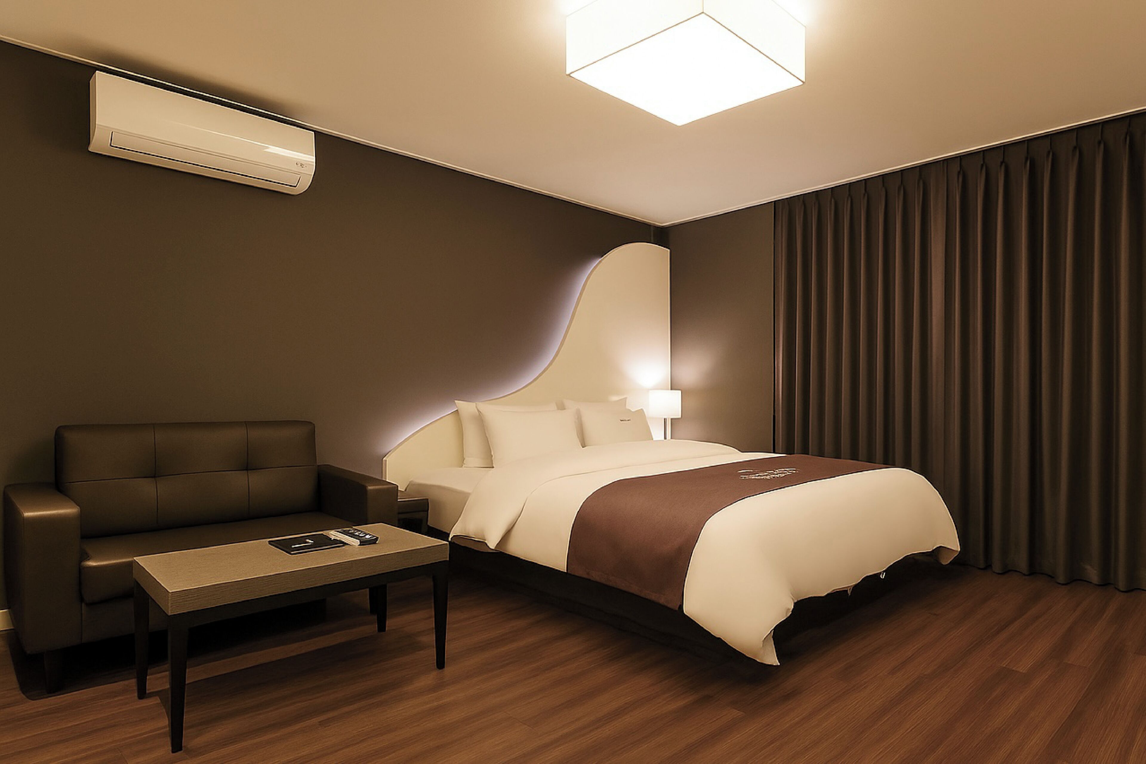 Una habitación de hotel con cama, sofá, mesa y aire acondicionado.