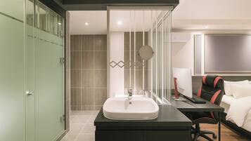A modern hotel bathroom with a sink, mirror, and shower area.