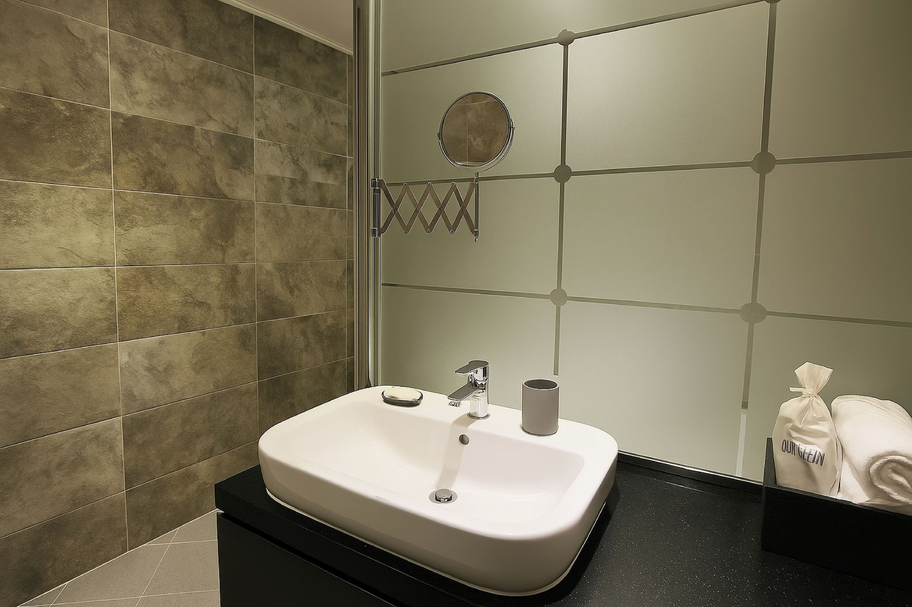 A bathroom with a white sink, a mirror, and a towel rack.