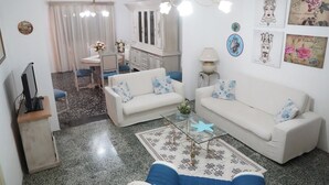A living room with a white sofa, a coffee table, and a dining area with a table and chairs. - Spacious family home (children 0/2 years stay free) dogs allowed (BORGAGNE)