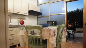A kitchen with a dining table and chairs, a microwave, and a window overlooking a garden. - Spacious family home (children 0/2 years stay free) dogs allowed (BORGAGNE)