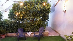 An outdoor seating area with two chairs and a table, surrounded by greenery and string lights. - Spacious family home (children 0/2 years stay free) dogs allowed (BORGAGNE)