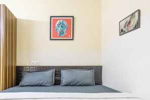 Un dormitorio con una cama, dos almohadas, un cabecero y dos cuadros enmarcados en la pared.