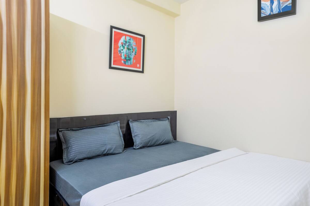A hotel room with a bed, two pillows, a headboard, and a framed picture on the wall.